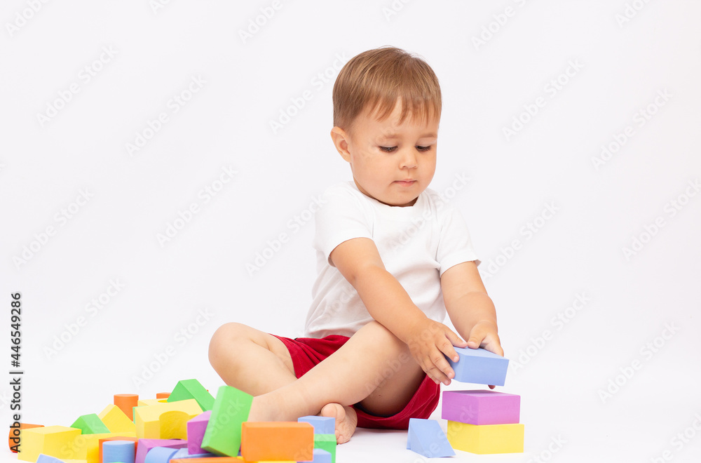 Laughing little boy playing with colorful blocks, isolated on white background Laughing little boy playing with colorful blocks, isolated on white background