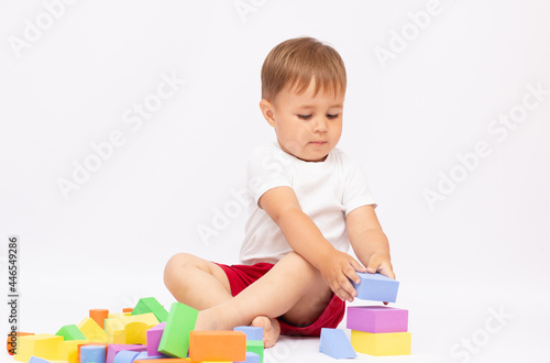 Laughing little boy playing with colorful blocks, isolated on white background