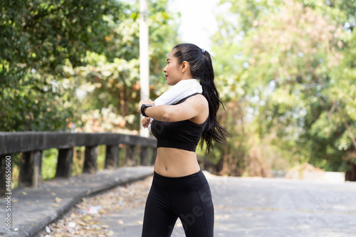Asian young woman wearing black sportswear doing stretching outdoor in the park. Sport woman warm up and exercise. Woman fitness outdoor