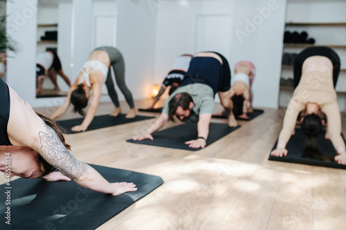 Blurred image of a group of people practicing yoga, doing downward facing dog photo