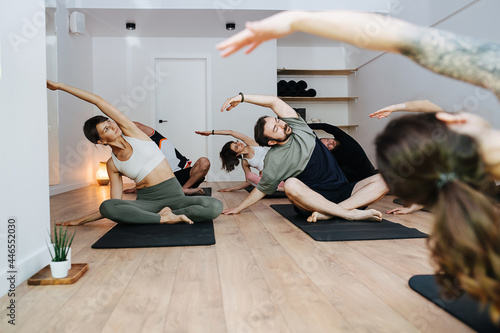 Group of people practicing yoga, side bending in easy pose photo