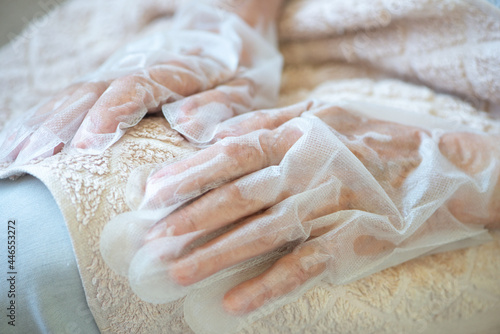 Senior woman wearing hand mask gloves. Moisturizing gloves to soften and protect hand skin.