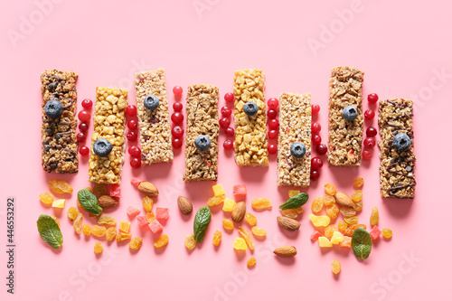 Healthy cereal bars, berries and nuts on color background