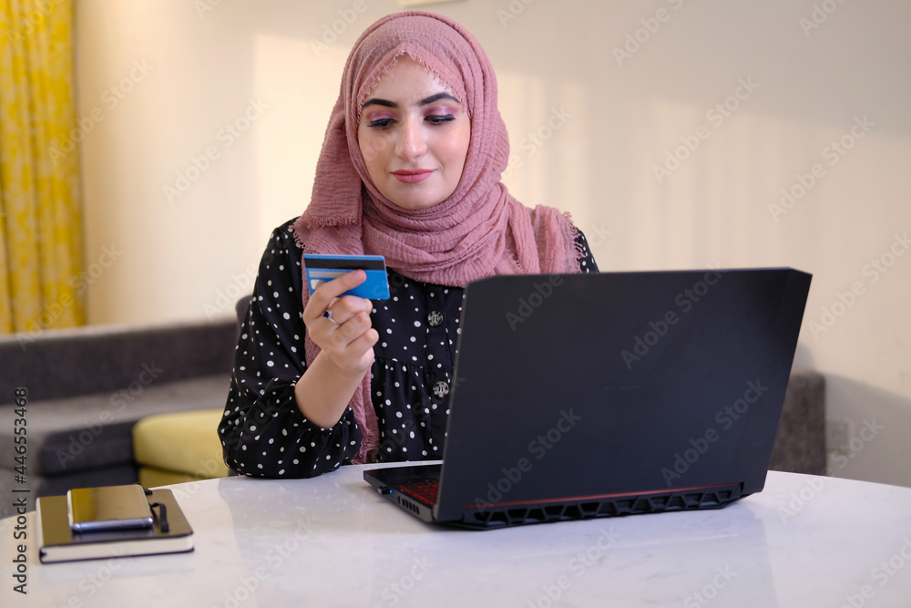 Online buying concept of a Arabic woman wearing head scarf as part of traditional custome using mobile cell phone. Emirati lady using mobile device browsing the internet or doing online banking Online buying concept of a Arabic woman wearing head scarf as part of traditional custome using mobile cell phone. Emirati lady using mobile device browsing the internet or doing online banking