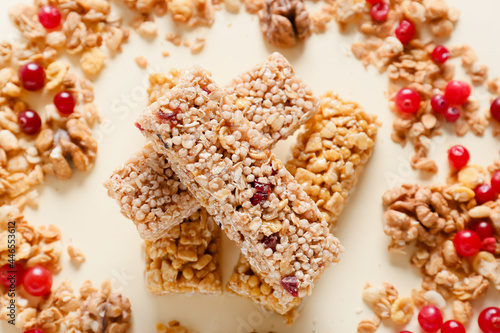 Healthy cereal bars and cranberries on color background