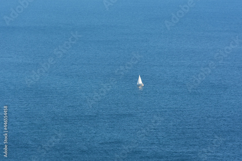 White sailboat sea. The endless blue sea, the concept of minimalism, loneliness, summer relaxation. A lone white boat is traveling in the ocean. Sea tourism, towards adventure. Top view, copy space
