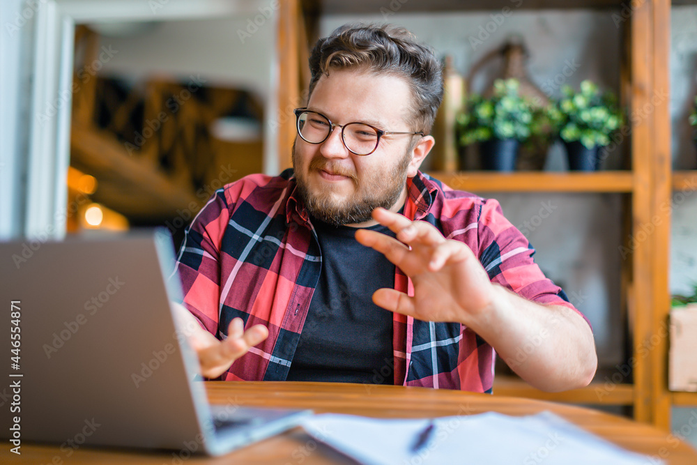 Obraz premium Photo of a friendly young man in in front of laptop monitor during online video call.