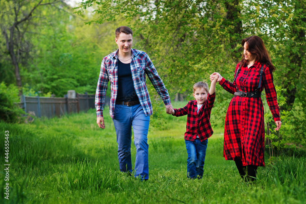 Happy family outdoors spending time together. Father, mother and son are having fun on a green grass in the park. International family day concept Happy family outdoors spending time together. Father, mother and son are having fun on a green grass in the park. International family day concept