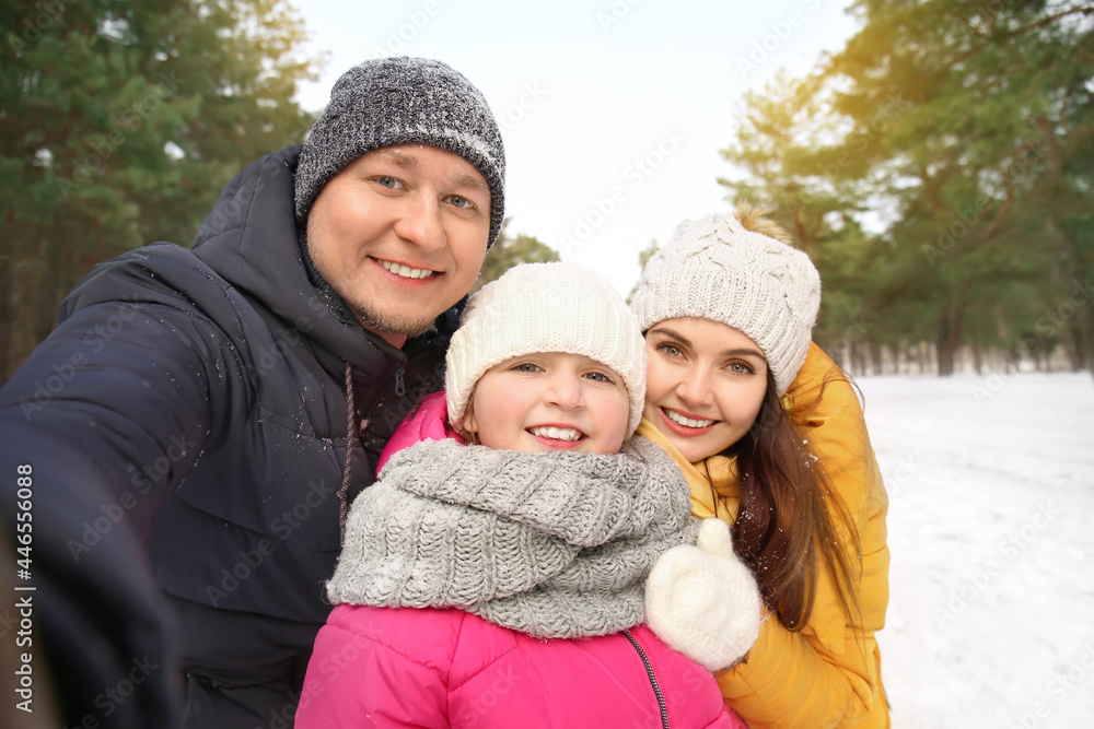 Happy family taking selfie in park on winter day