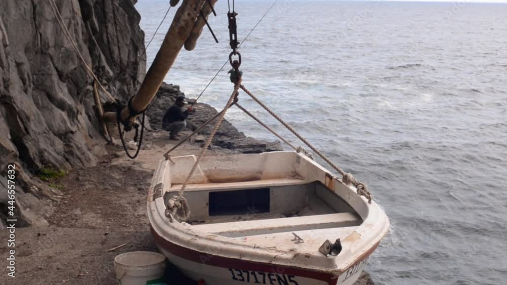 A Man is Fishing on A Cliff near a Boat Lift System for dry storage, Handheld