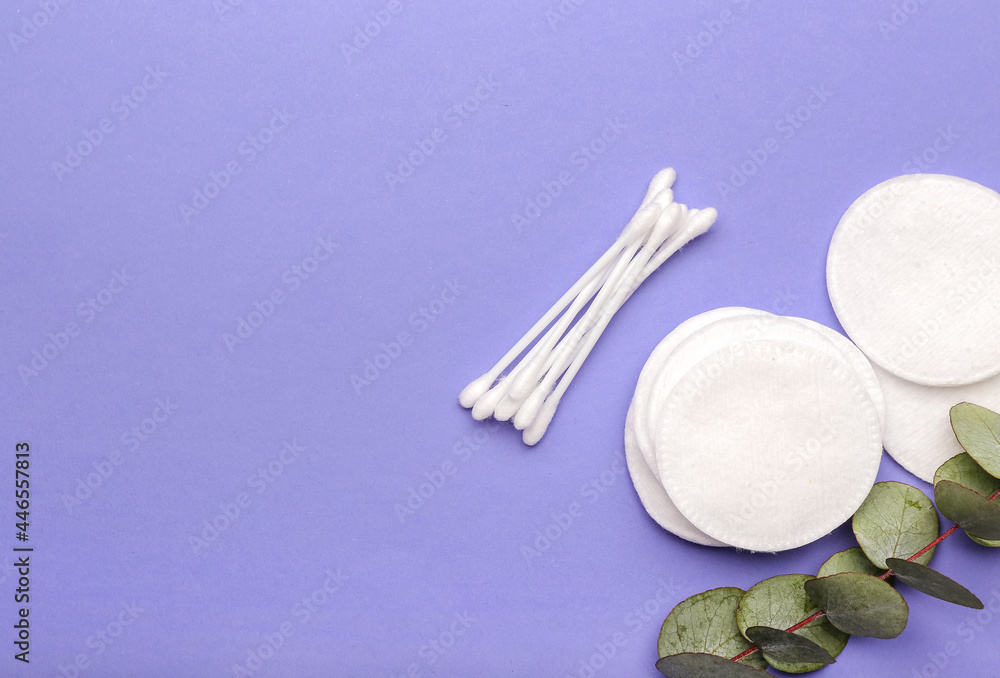 Fototapeta premium Cotton pads, swabs and eucalyptus branch on color background