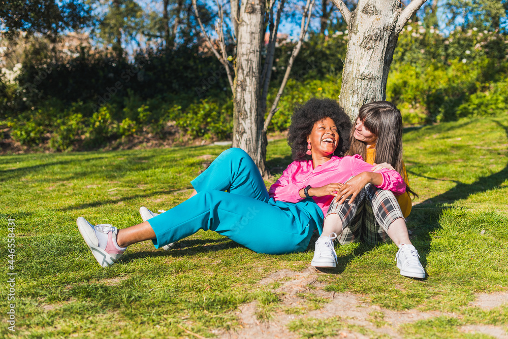 Happy multiethnic lesbian couple hugging in summer park Happy multiethnic lesbian couple hugging in summer park