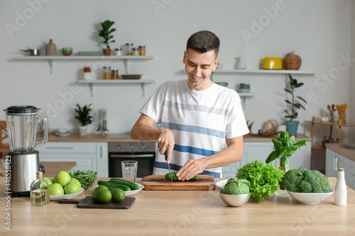 Young man cutting cucumber ...