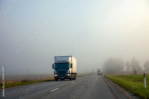 Truck on a country road in the fog in summer. Poor visibility conditions on the road.