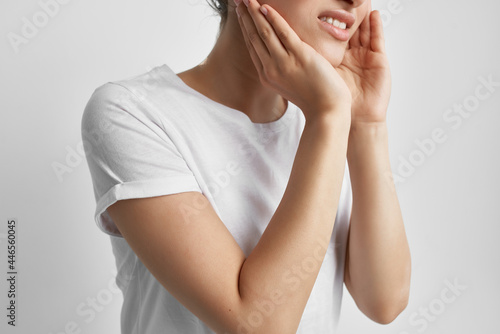 woman in white t-shirt holding face pain in teeth health problems treatment