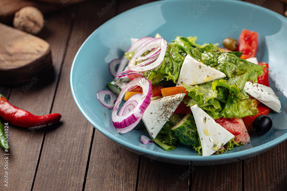 Plate of greek salad with fresh vegetables on wooden decorated background Plate of greek salad with fresh vegetables on wooden decorated background