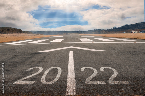 White arrow on a small asphalt air plane runway. Cloudy sky with