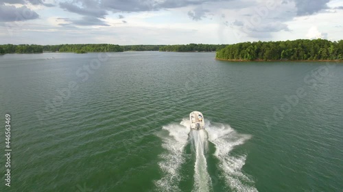 Aerial view of lake and boat running in the water. Green lake with green trees in the summer photo