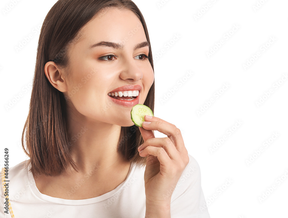 Young woman eating cucumber on white background, closeup