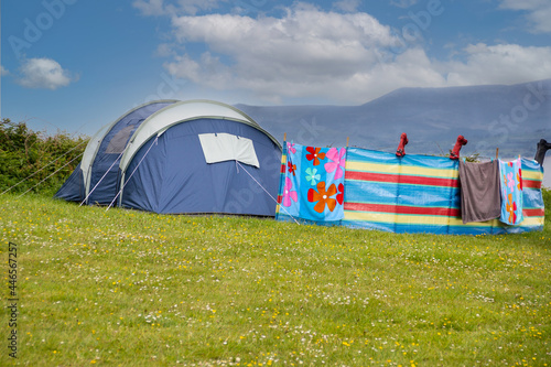 Staycations are go-tent with towels drying and wellies drying upside down on windbreak as family enjoy a summers break in Harlech Wales.