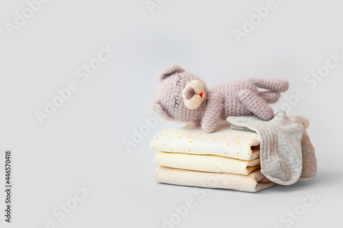 Fototapeta Naklejka Na Ścianę i Meble -  Stack of baby clothes and knitted toy on grey background