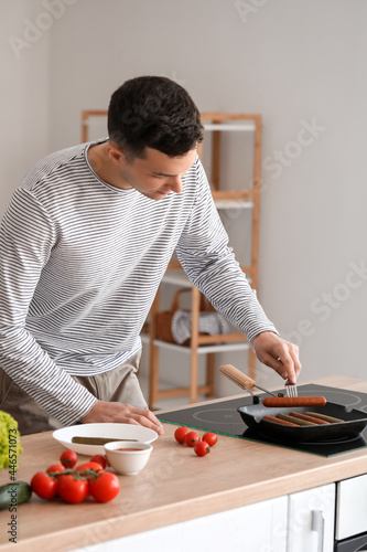 Young man frying tasty saus...