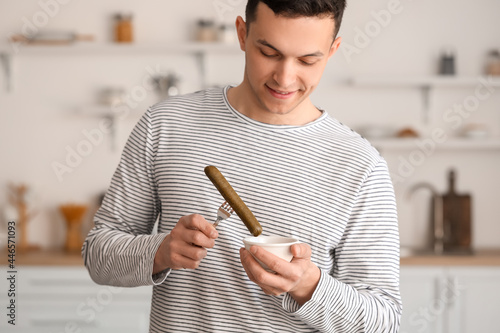 Young man with tasty sausag...