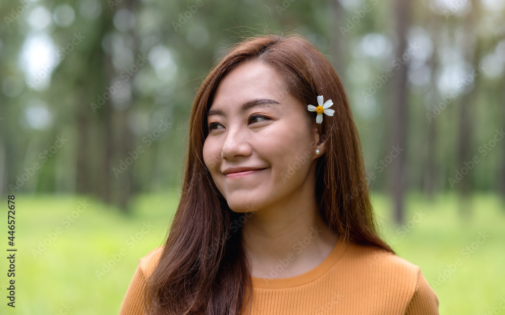 Portrait image of a beautiful young asian woman putting Biden Alba or Spanish needles flower behind her ear
