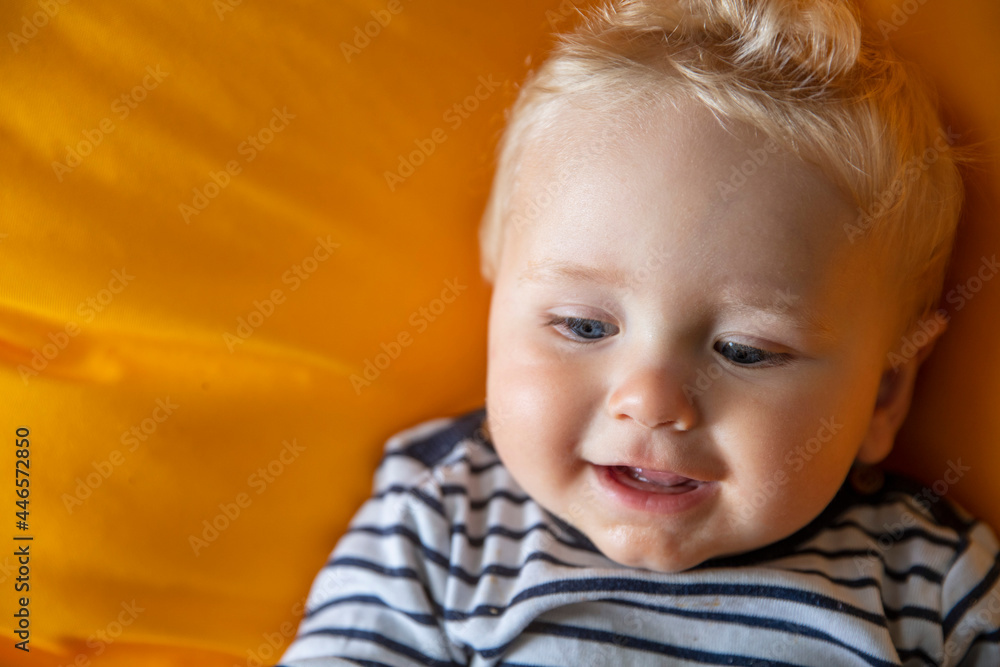 Close up of a cute 9 month old baby boy with blue eyes on a yellow background Close up of a cute 9 month old baby boy with blue eyes on a yellow background