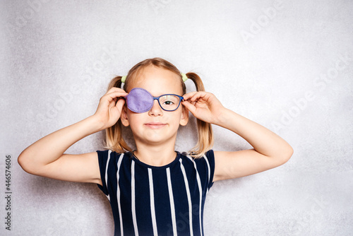 Fotografija Happy little girl wearing glasses and eye patch or occluder, amblyopia (lazy eye
