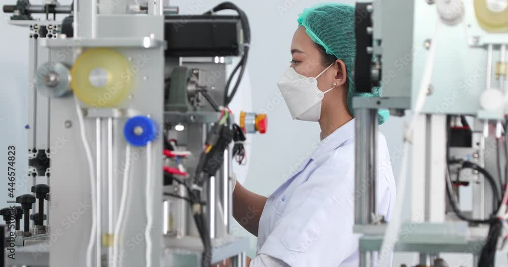 Asian female worker in sterile cloths working in face mask production line factory. Surgical Face mask production, industry factory and people concept