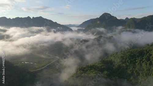 drone flies up to reveal misty mountain range with mountain pass in sunrise photo