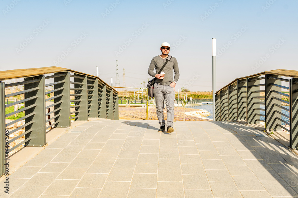 Young man crossing a bridge on a sunny autumn day.