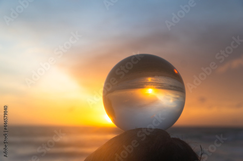 beautiful cloud and golden sunset inside crystal ball placed on a timber beside the beach..beautiful nature in a crystal ball by the sea..Unique and creative travel and nature idea.. © Narong Niemhom