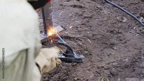 A worker welder using a welding machine welds a metal structure during construction, industry
