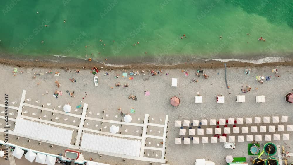 Aerial time lapse beach. busy beach full of people. timelapse life view from above. green and blue sea waves roll ashore, people swim in water and sunbathe on shore crammed colorful umbrellas. Aerial time lapse beach. busy beach full of people. timelapse life view from above. green and blue sea waves roll ashore, people swim in water and sunbathe on shore crammed colorful umbrellas.