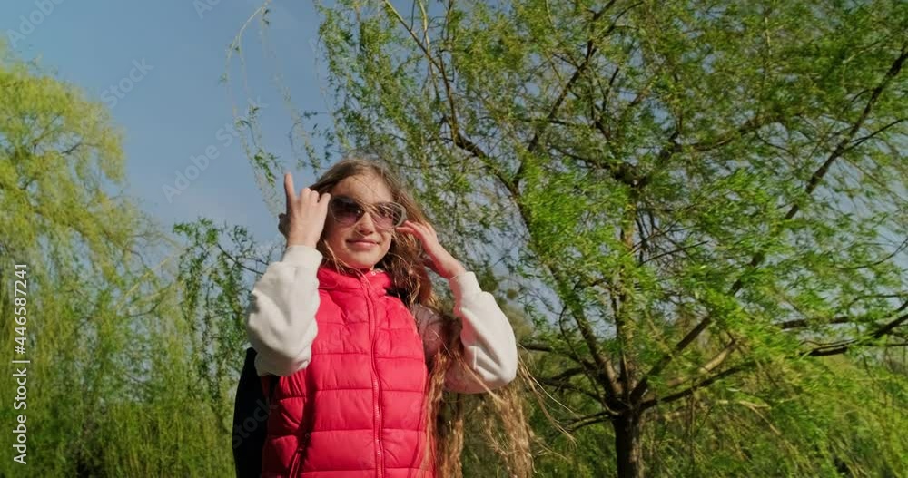 Preteen girl in sunglasses walking in the park in windy weather. Slow motion Preteen girl in sunglasses walking in the park in windy weather. Slow motion
