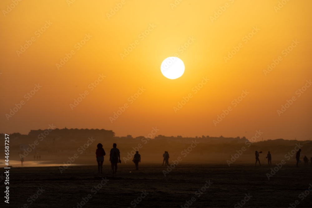 sunset on the beach of huelva with silhouettes of people