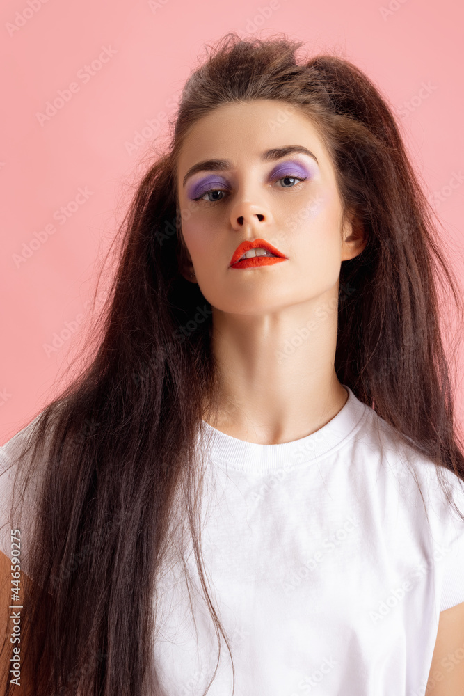 Close-up adorable pretty young girl with bright makeup and hairdo in retro 90s fashion style isolated over pink studio background. Concept of eras comparison, beauty, fashion and youth. Close-up adorable pretty young girl with bright makeup and hairdo in retro 90s fashion style isolated over pink studio background. Concept of eras comparison, beauty, fashion and youth.
