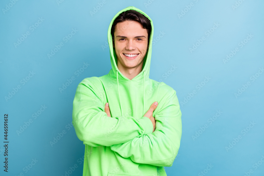 Photo of positive self-assured guy folded arms look camera wear green sweatshirt isolated blue color background Photo of positive self-assured guy folded arms look camera wear green sweatshirt isolated blue color background