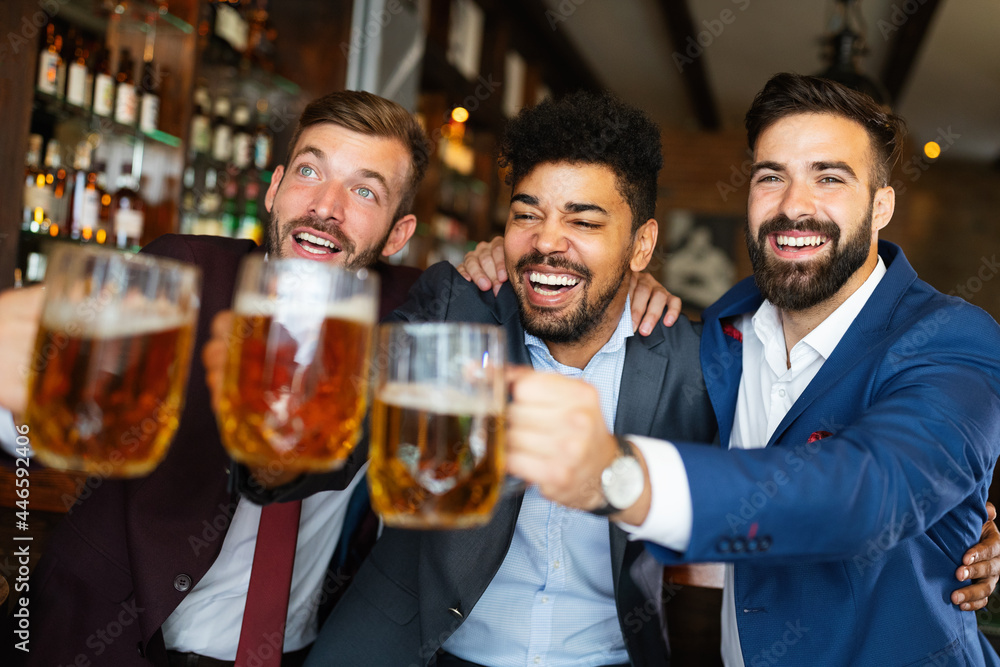 Young businessmen are drinking beer, talking and smiling while resting at the pub