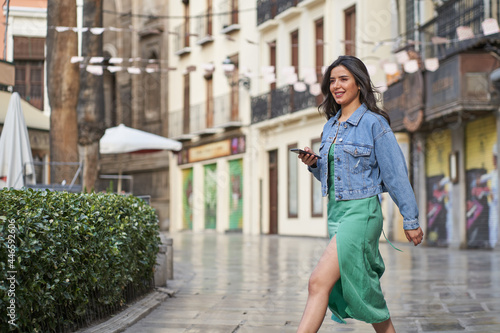 woman walking with smartphone in hand through the city