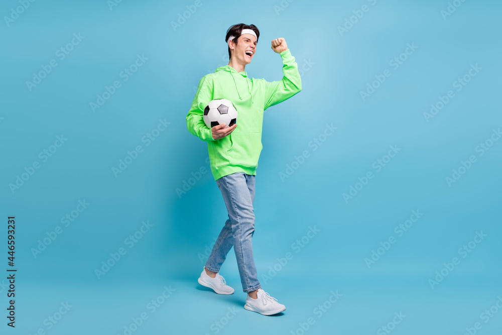 Photo of handsome lucky young gentleman wear green sweatshirt smiling winning football game isolated blue color background Photo of handsome lucky young gentleman wear green sweatshirt smiling winning football game isolated blue color background