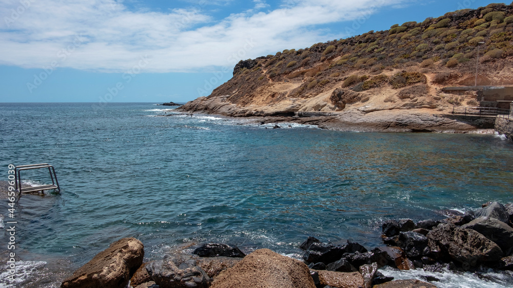 Secluded natural bay in La Caleta, little resort in Costa Adeje with volcanic arid coast and crystal clear waters suitable for swimming and enjoying a day by the sea in Tenerife, Canary Islands, Spain