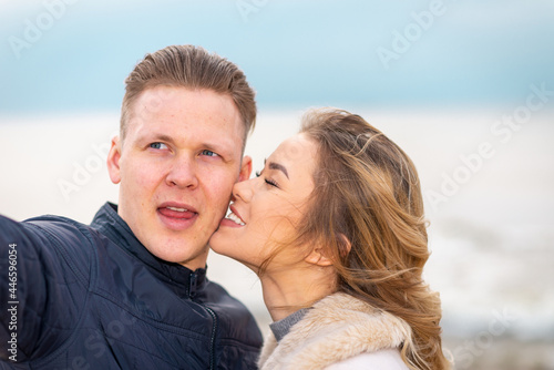 Beautiful young happy woman hugging cuddle young boyfriend while taking selfie photo on sunny beach.Close up.