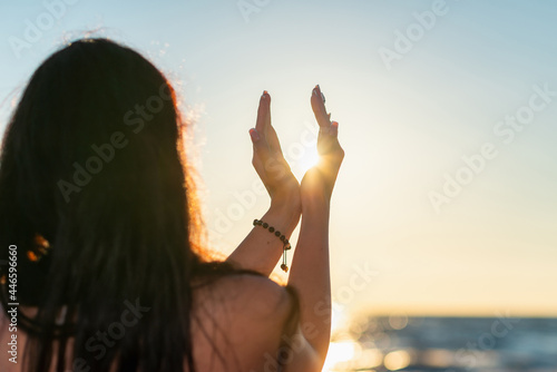 Tableau sur toile Silhouette of young woman's hands relaxing, happy meditating and holding sunset against golden hour sky on the beach