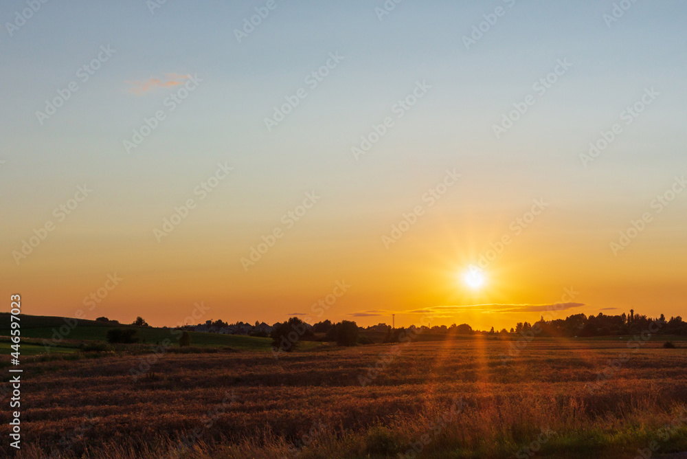 Rural Landscape sunset with sun natural sunray sunflare. Rising above horison.Nice summer golden field,forest evening
