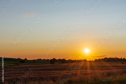 Rural Landscape sunset with sun natural sunray sunflare. Rising above horison.Nice summer golden field,forest evening
