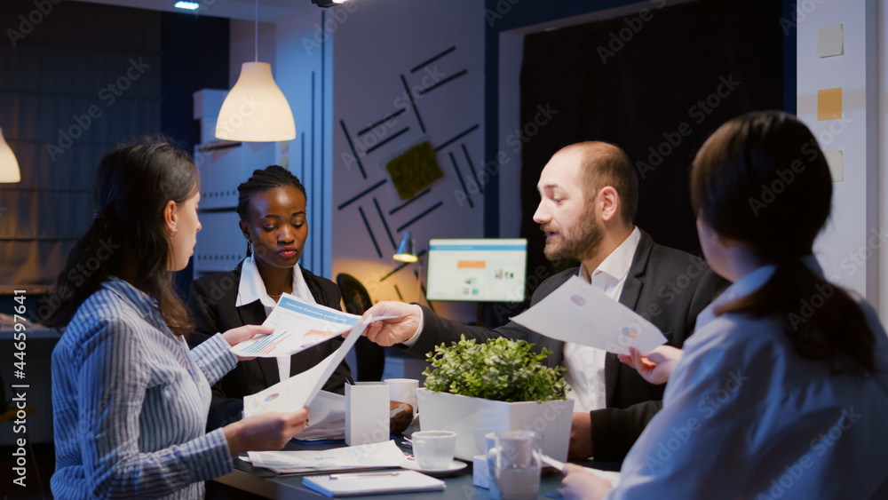 Multi ethnic business teamwork analyzing management presentation sharing financial graphs paperwork overworking office meeting room late at night. Coworkers brainstorming company ideas Multi ethnic business teamwork analyzing management presentation sharing financial graphs paperwork overworking office meeting room late at night. Coworkers brainstorming company ideas