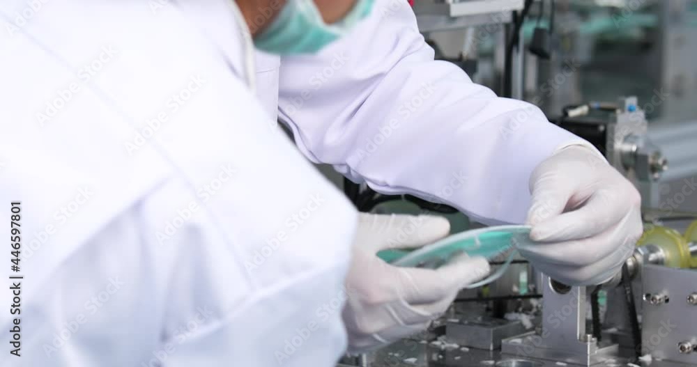 Male worker in sterile cloths working in face mask production line factory. Surgical Face mask production, industry factory and people concept Male worker in sterile cloths working in face mask production line factory. Surgical Face mask production, industry factory and people concept